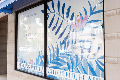 Storefront window with floral graphic showing Coming Fall 2022