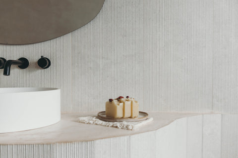 Three bars of soap displayed on a dish that is on the bathroom counter