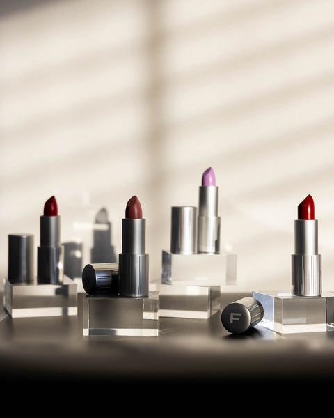 Closeup of four different color lipstick sets on acrylic risers