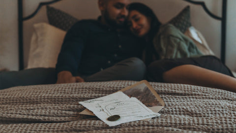 Couple in the background cuddling on a bed, with RSVPs in the foreground