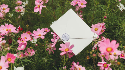Wax-sealed letter laying on a bed of pink flowers